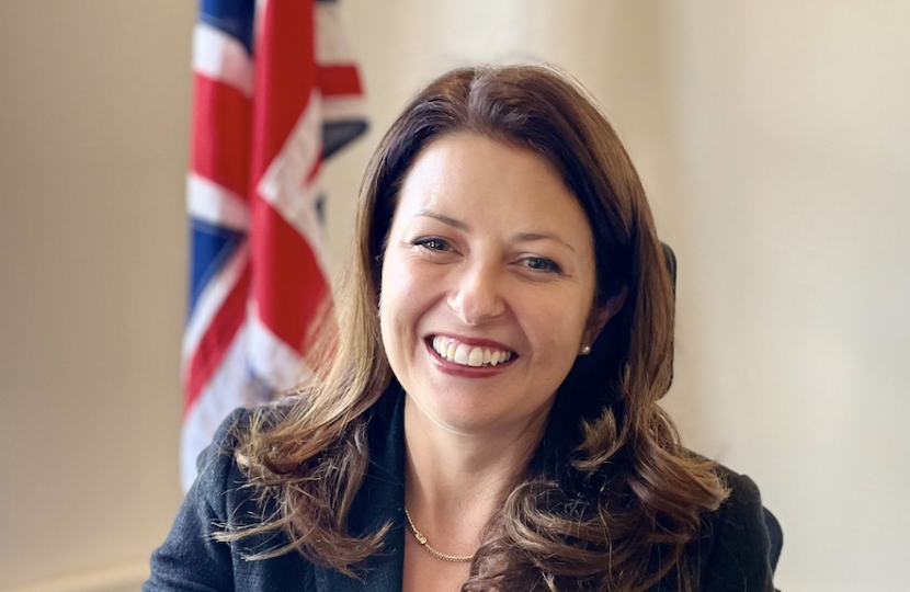 Joy at her desk with UK flag behind 